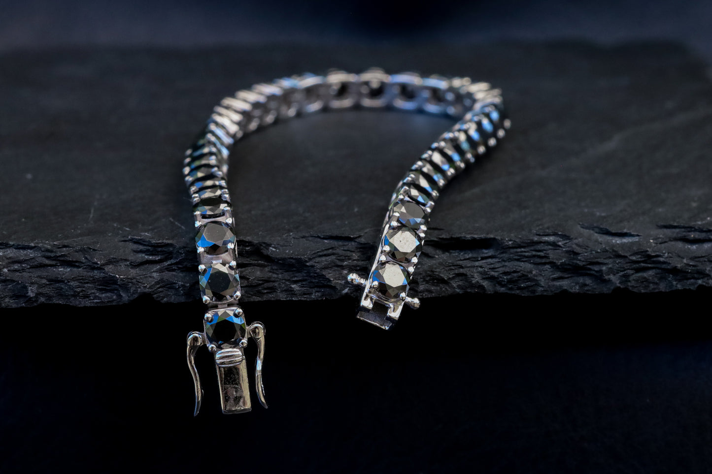 Silver bracelet with black moissanite gem stones on a dark stone surface