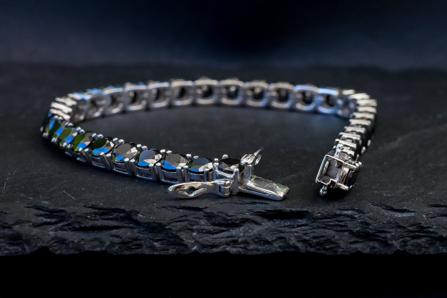Silver bracelet with black moissanite gemstones on a dark surface